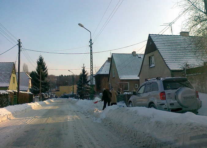 Panowie solidarnie odśnieżają chodnik - rzucając śnieg  prosto na ulicę