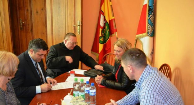 Burmistrz Marcin Orzeszek z radnym Piotrem Rogowskim, sołtyską Izabelą Skowron-Cisak i księdzem Stanisławem Jendykiewiczem podczas podpisywania umowy