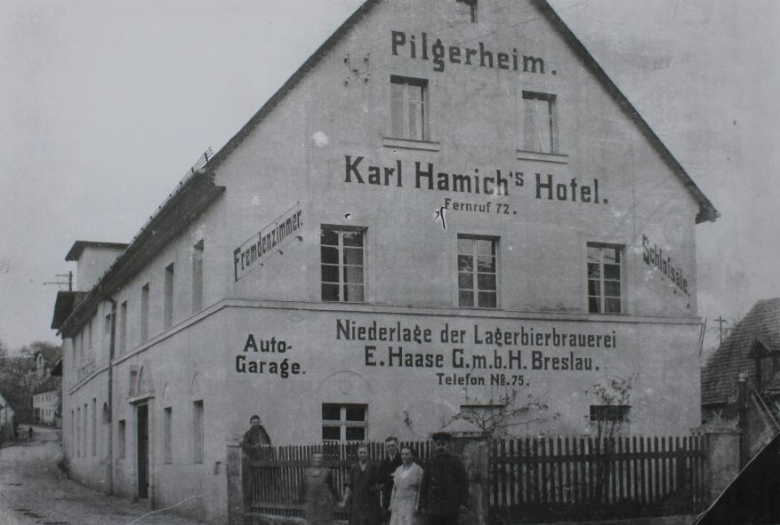 Zdjęcie wykonane po 1914 r. Napis na ścianie na parterze informuje o znajdującym się tutaj składzie piwa spółki E. Haase z Wrocławia. W tle, po lewej stronie, znajduje się charakterystyczny wysoki budynek z płaskim dachem dawnej słodowni